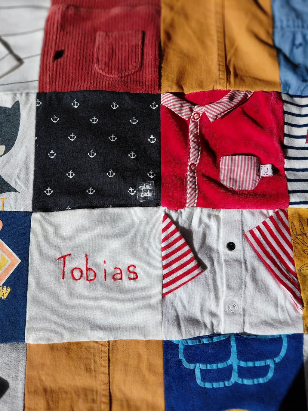 Détail de la couverture souvenir garçon personnalisée avec son prénom brodé. La couverture personnalisée unique est confectionnée en France à partir des habits troué ou salit. Redonnez vie à ses tenues.